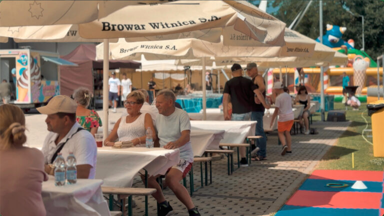 Menschen entspannen sich an Tischen unter großen Sonnenschirmen